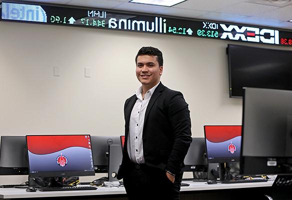 Student standing in front of stock ticker